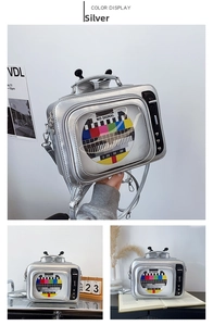 Detail of silver TV-shaped crossbody bag featuring NO SIGNAL pattern and top handle