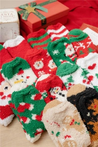 Detailed macro of festive coral fleece Christmas socks featuring Santa and reindeer patterns