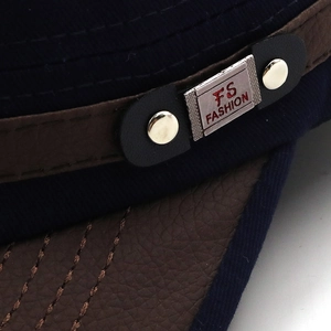Detail of navy blue fabric cap with embossed brown leather band and FS FASHION metal plate