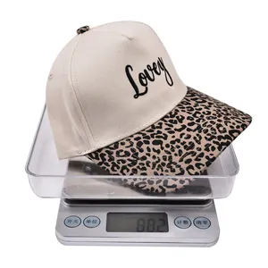 Detailed view of an embroidered cotton cap with leopard print brim on a digital scale
