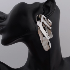 Irregular silver metallic wavy earrings with glossy finish on elegant display
