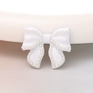 Macro view of a white bow accessory with neat rows of inlaid pearls for DIY crafts