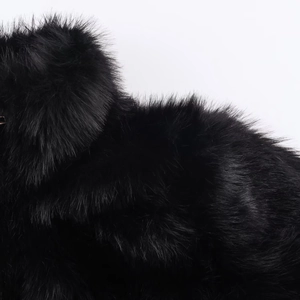 Gros plan du manteau en fausse fourrure noire montrant la texture dense et le lustre