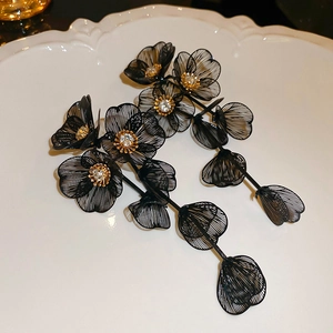 Detailed macro of black mesh flower earrings with sparkling rhinestones in white dish