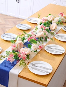 Detailed view of pink rose garland and faux greenery as an elegant dining table runner