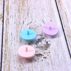 Detail of colorful plastic spinning top pencil toppers in blue, purple, and pink shades