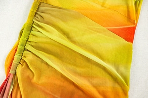 Detailed macro view of yellow and orange gradient pleated mesh fabric on evening dress