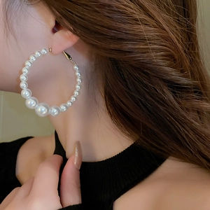 Detailed view of oversized hoop earrings with gradient white pearls on gold-toned wire