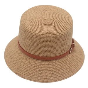 Detail of woven straw hat featuring a brown leather belt strap and gold buckle