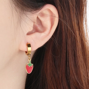 Close-up of a model wearing sweet strawberry drop earrings with red enamel and gold rings