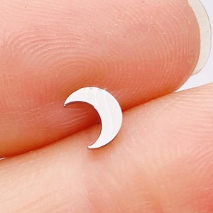 Macro shot of silver moon-shaped stainless steel stud earring held by fingers