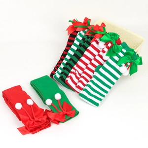 Christmas over-knee bow socks with stripes and pom-poms shown in flat lay and basket