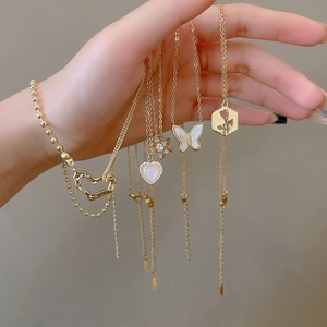 Elegant gold titanium steel necklaces with zircon pendants shown on a model hand