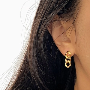 Golden stainless steel Cuban chain earrings shown on model in a minimalist style