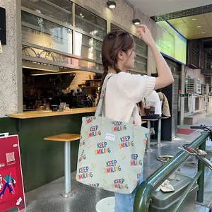 Outdoor lifestyle shot of a large light green corduroy tote bag with Keep Smiling print