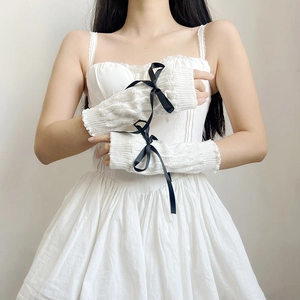 Close-up of white knitted sleeves with black ribbon bows in a sweet Lolita style