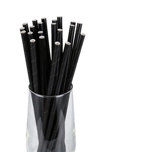 Eco-friendly black paper straws with spiral texture in a clear glass on white background