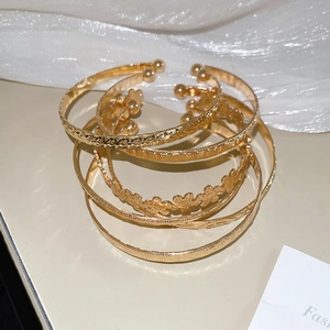 Détails d'un ensemble de six bracelets dorés avec motifs floraux et étoiles gaufrés