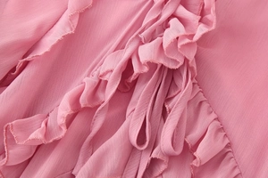 Détail d'une robe rose à volants montrant le tissu texturé léger et les coutures