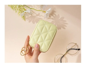 Close-up of quilted pale green mini makeup bag with golden zipper and keychain