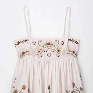 Sleeveless off-white cotton dress featuring colorful floral embroidery and thin straps
