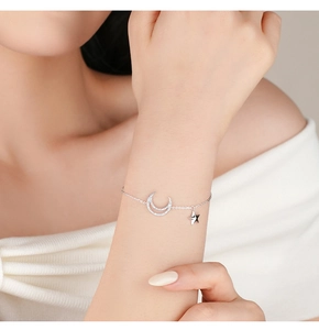 Detail showing the silver moon and star bracelet adorned with sparkling cubic zirconia