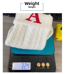 Detailed scale view showing the 32.4g weight of white knitted Christmas stocking with letter A