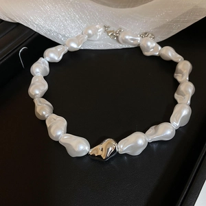 Détail du collier de perles baroques avec pendentif cœur argenté sur plateau noir