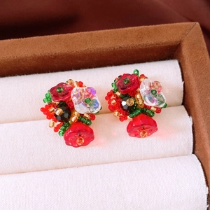 Detail of vintage style beaded flower earrings with red petals and silver needle studs