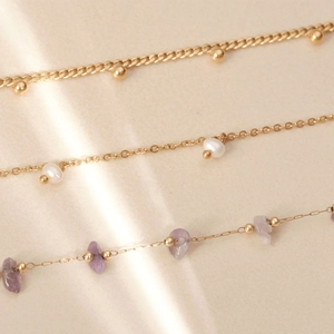 Detailed macro view of 18K gold plated chains with pearls and purple natural stones