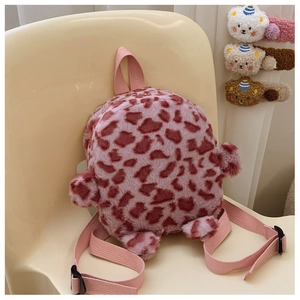 Detail of pink leopard plush kids backpack with bear ears on a soft yellow chair