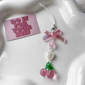 Detailed close-up of handmade pink cherry and strawberry beaded phone strap on ceramic plate