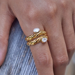 Detailed shot of golden twisted rope double ring with sparkling white pear-cut zircon crystals