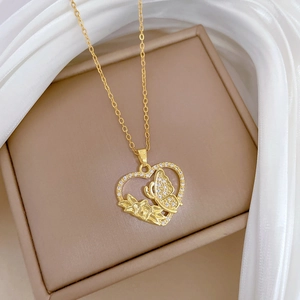 Close-up of golden heart pendant with butterfly design and crystals on silk fabric