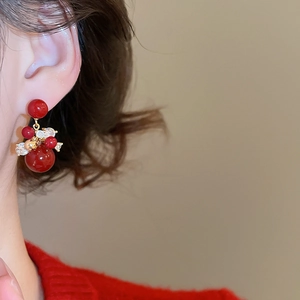 Detail of gold-plated red zircon festive earrings showing textures and sparkle on model