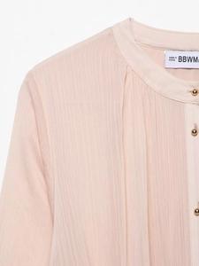 Detail of light pink pleated chiffon dress with gold buttons and standing collar