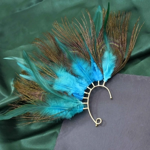 Macro detail of vintage peacock feather ear cuff with vibrant green and blue plumes