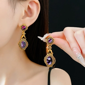 Detailed close-up of vintage golden earrings with oval purple stones and ornate patterns