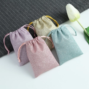 Detailed view of shimmering drawstring jewelry pouches in pink, purple, gold and teal colors