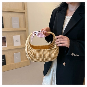 Detail of hand-woven rattan basket bag with decorative pink floral scarf on handle