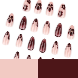 Short almond press-on nails with pink floral patterns and burgundy cat-eye finish