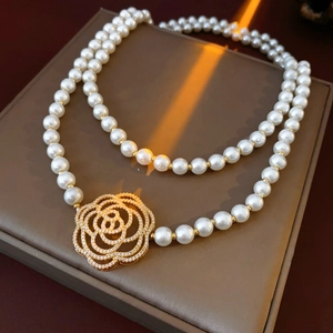 Detail of double-layer pearl necklace with golden camellia diamond pendant on jewelry box