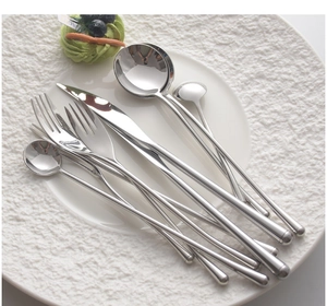 Macro view of mirror polished 304 stainless steel cutlery set on a white ceramic plate
