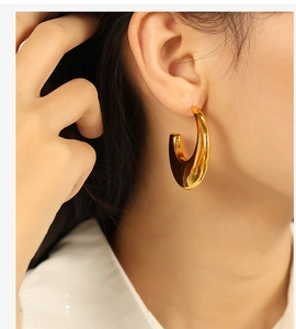 Close-up of gold geometric C-shaped hoop earrings worn by a model for a stylish look