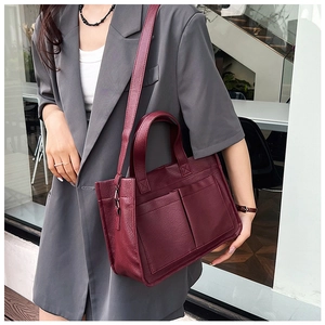 Detail of dark red tote bag with dual front pockets and adjustable shoulder strap