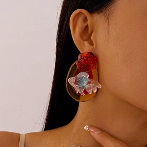 Close-up of vintage resin flower and goldfish earrings worn on a model's ear