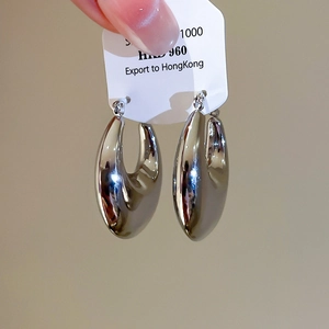 Macro detail of thick silver U-shaped hoop earrings with a mirror-polished finish