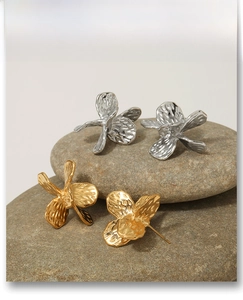 Detail of flower stud earrings with hammered metal texture in gold and silver finish
