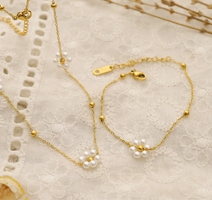 Detailed shot of gold floral pearl necklace and bracelet set on white lace fabric