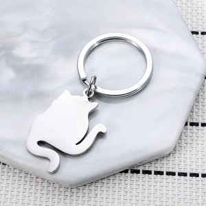 Polished silver stainless steel cat silhouette keychain on marble coaster background